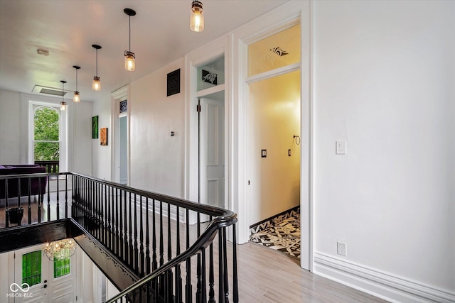 hall featuring wood finished floors, an upstairs landing, and baseboards