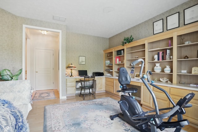 12065 Gray Eagle Dr, Fishers, IN 46037 - office area with built in desk, wallpapered walls, and light wood-type flooring