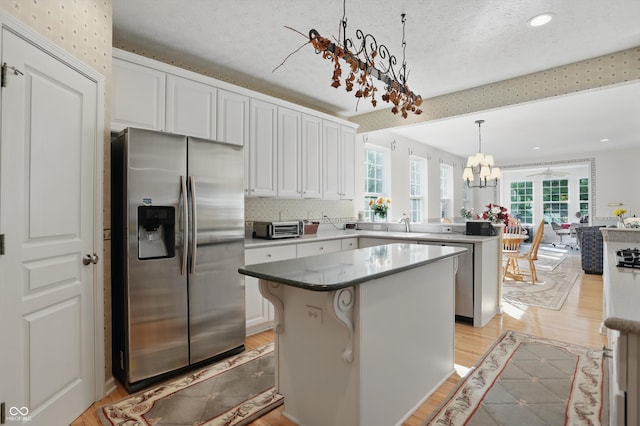 12065 Gray Eagle Dr, Fishers, IN 46037 - kitchen with stainless steel fridge, a peninsula, a chandelier, a kitchen island, and white cabinets