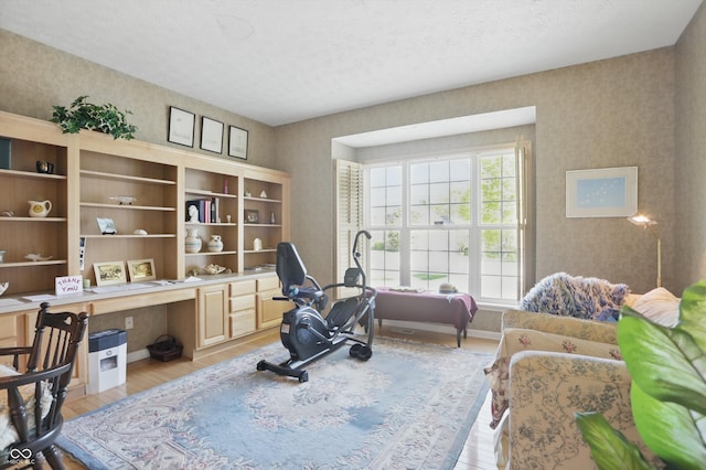 12065 Gray Eagle Dr, Fishers, IN 46037 - home office with light wood-style floors, a textured ceiling, wallpapered walls, and built in study area