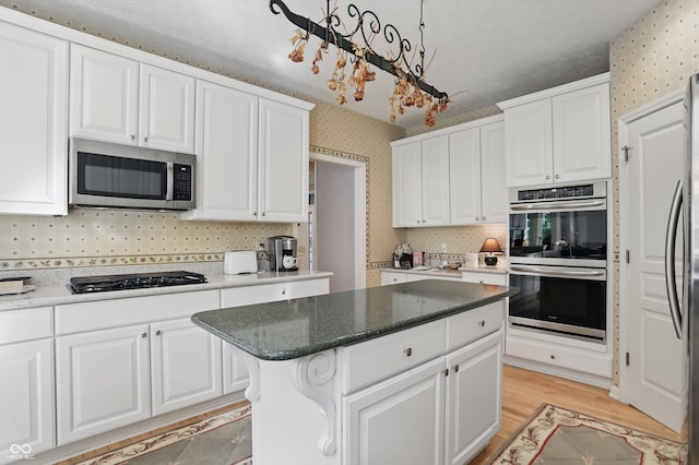 12065 Gray Eagle Dr, Fishers, IN 46037 - kitchen with appliances with stainless steel finishes, wallpapered walls, white cabinetry, light wood-type flooring, and decorative backsplash
