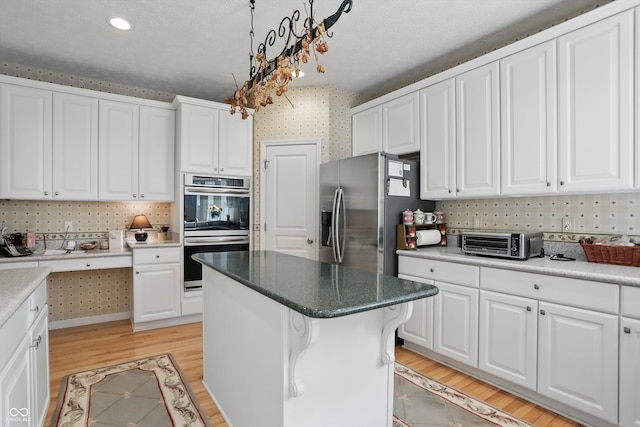 12065 Gray Eagle Dr, Fishers, IN 46037 - kitchen with stainless steel appliances, light wood-style floors, white cabinetry, backsplash, and a center island