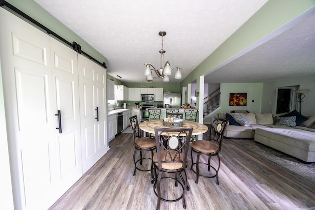 1334 Legacy Ct, Indianapolis, IN 46234 - dining room with a barn door, stairway, wood finished floors, a textured ceiling, and a chandelier