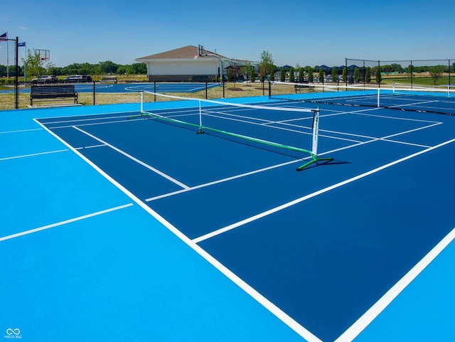 view of tennis court featuring community basketball court and fence