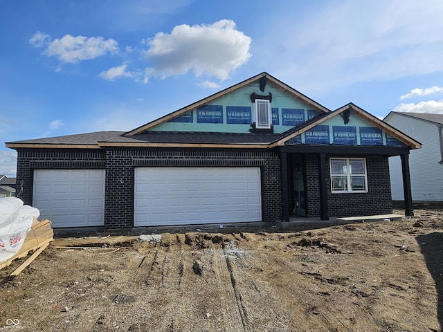 view of front of house featuring dirt driveway, brick siding, and an attached garage
