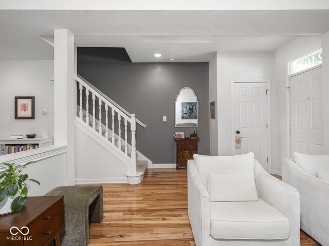 living area with light wood-style floors, stairs, baseboards, and recessed lighting