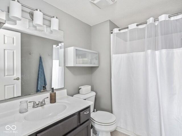 full bathroom featuring toilet, vanity, a textured ceiling, and a shower with curtain