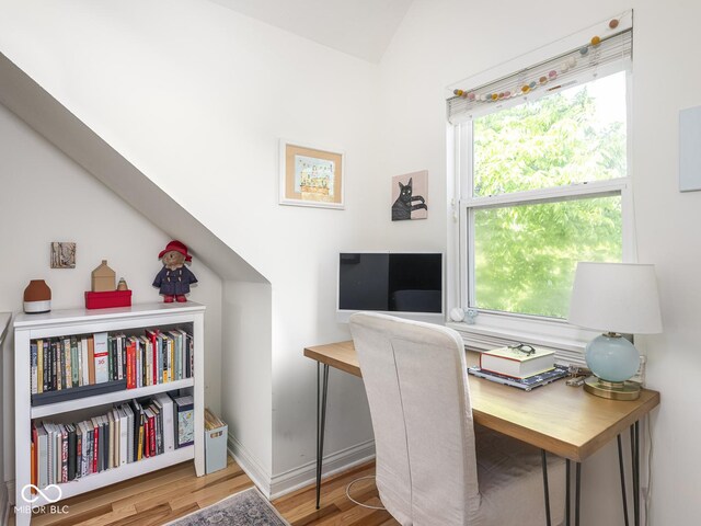 home office featuring healthy amount of natural light, wood finished floors, baseboards, and lofted ceiling