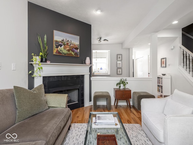 living area with stairway, a tiled fireplace, wood finished floors, and recessed lighting