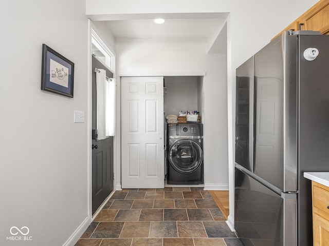 clothes washing area featuring washer / dryer, baseboards, and stone finish floors