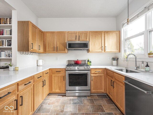 kitchen with appliances with stainless steel finishes, a sink, light countertops, and stone finish floors