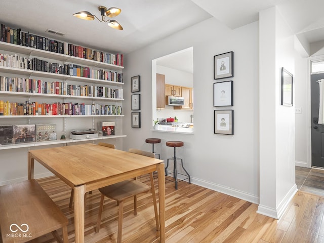 dining room with light wood-type flooring, baseboards, and a chandelier