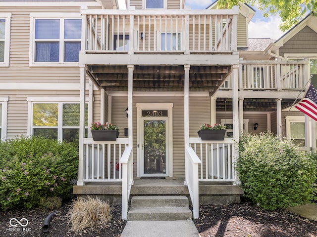 doorway to property with a balcony and a porch