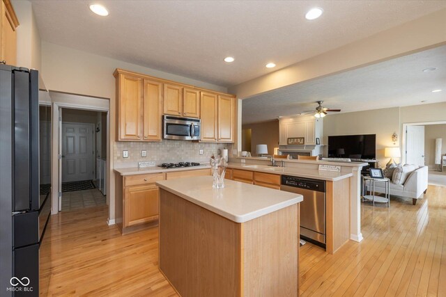 14018 Powder Dr, Carmel, IN 46033 - kitchen with stainless steel appliances, open floor plan, a peninsula, light wood finished floors, and a sink