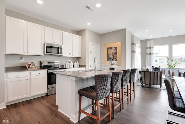 1075 Marston Ln, Avon, IN 46123 - kitchen with stainless steel appliances, a sink, dark wood-type flooring, a breakfast bar area, and white cabinetry