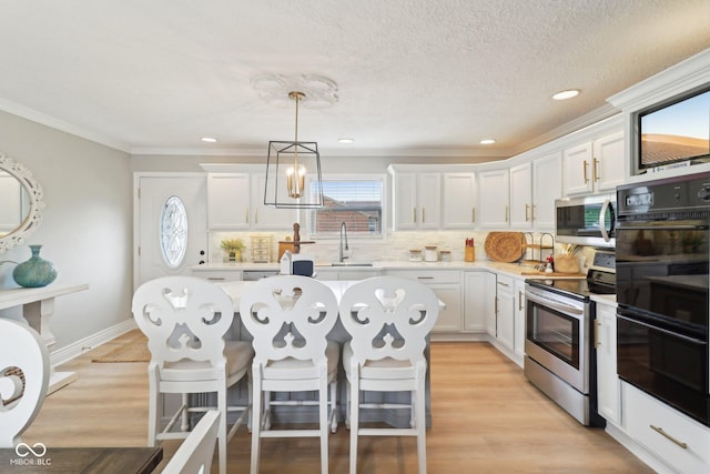 4732 Ferguson Rd, Indianapolis, IN 46239 - kitchen featuring stainless steel appliances, a sink, white cabinets, a kitchen breakfast bar, and ornamental molding