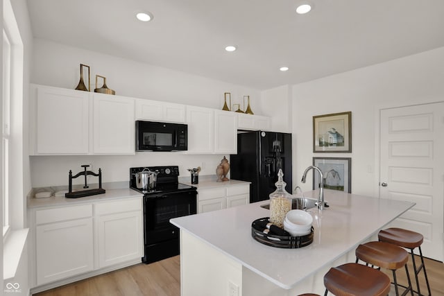 kitchen with black appliances, light wood finished floors, white cabinets, and recessed lighting