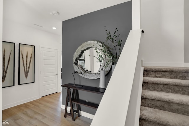 stairs with wood finished floors, recessed lighting, and baseboards
