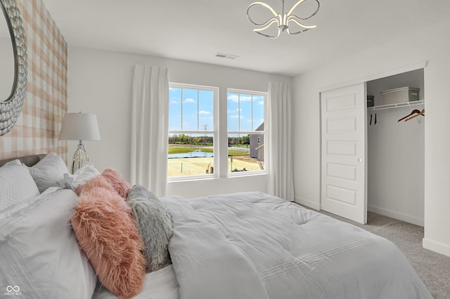 carpeted bedroom with a chandelier, baseboards, and a closet