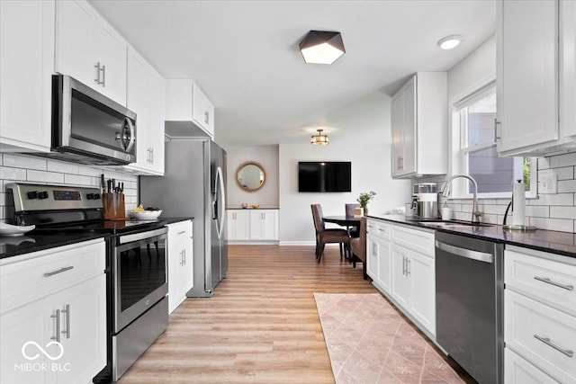 10444 Collingswood Ln, Fishers, IN 46037 - kitchen featuring stainless steel appliances, dark countertops, backsplash, light wood-style floors, and a sink