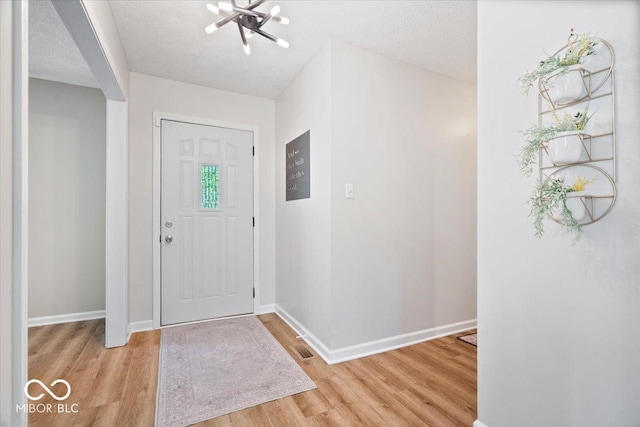 10444 Collingswood Ln, Fishers, IN 46037 - entrance foyer with a chandelier, light wood-style flooring, baseboards, and a textured ceiling