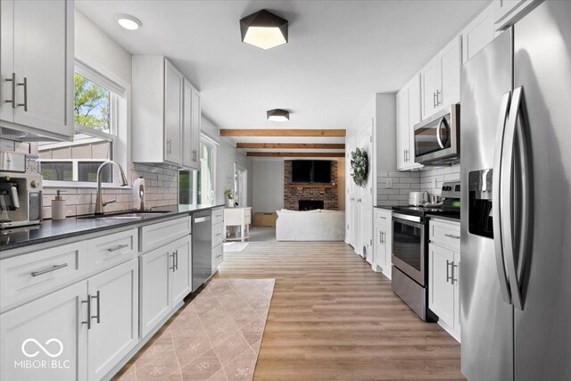 10444 Collingswood Ln, Fishers, IN 46037 - kitchen featuring stainless steel appliances, a sink, dark countertops, decorative backsplash, and beam ceiling
