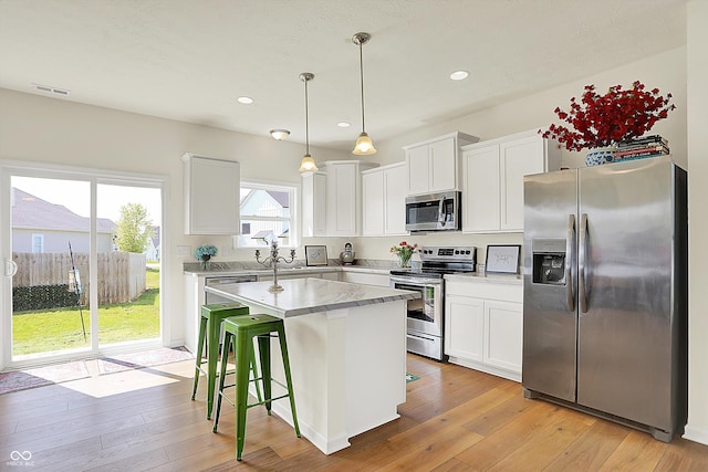 49 Manchester Dr, Trafalgar, IN 46181 - kitchen with appliances with stainless steel finishes, light wood-type flooring, a kitchen island, white cabinets, and recessed lighting