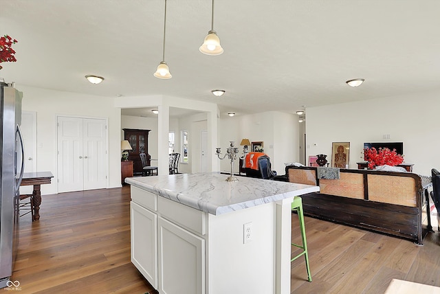 49 Manchester Dr, Trafalgar, IN 46181 - kitchen featuring hardwood / wood-style flooring, freestanding refrigerator, a center island, and white cabinetry