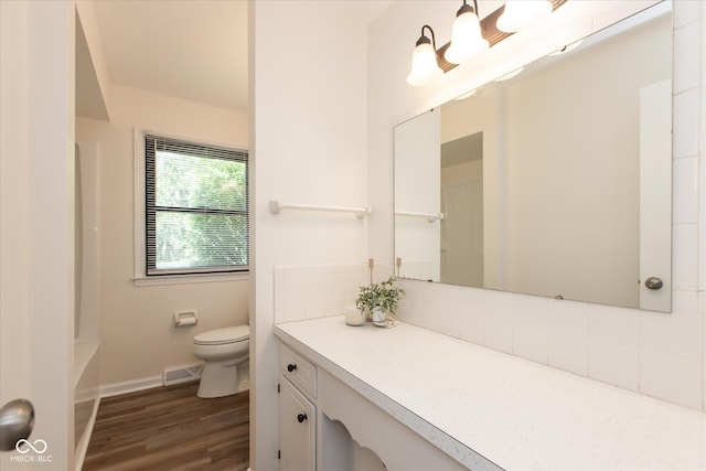 full bath featuring toilet, decorative backsplash, wood finished floors, vanity, and baseboards
