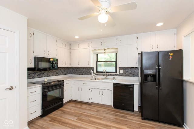 kitchen featuring black appliances, a sink, white cabinets, light countertops, and recessed lighting