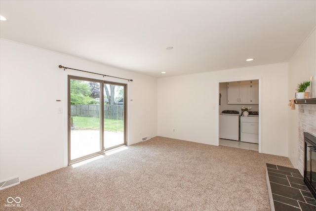 unfurnished living room featuring washer and clothes dryer, light carpet, a brick fireplace, and recessed lighting
