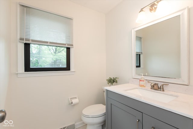 bathroom featuring toilet, vanity, and baseboards
