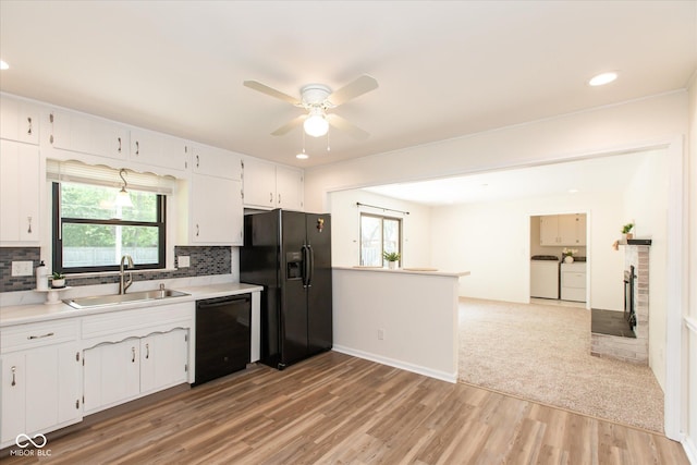 kitchen featuring a sink, black appliances, washer and dryer, ceiling fan, and light wood finished floors