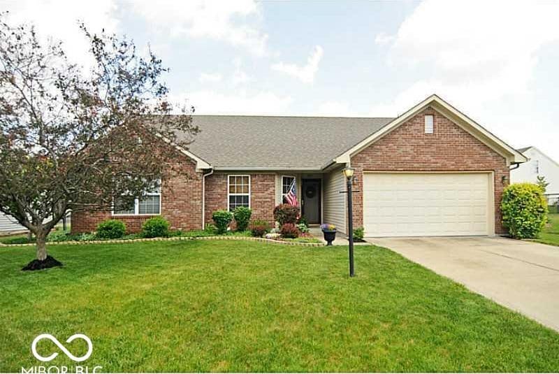 single story home with brick siding, a garage, concrete driveway, and a front lawn