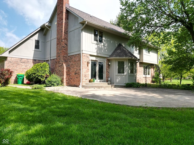 11021 Brentwood Ave, Zionsville, IN 46077 - back of property featuring a chimney, brick siding, a yard, and roof with shingles