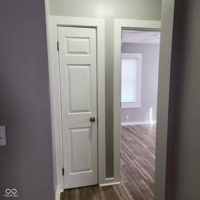 corridor with dark wood-type flooring and baseboards