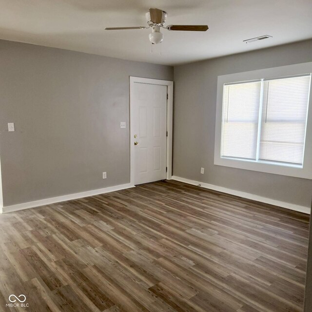 spare room featuring wood finished floors, a ceiling fan, and baseboards