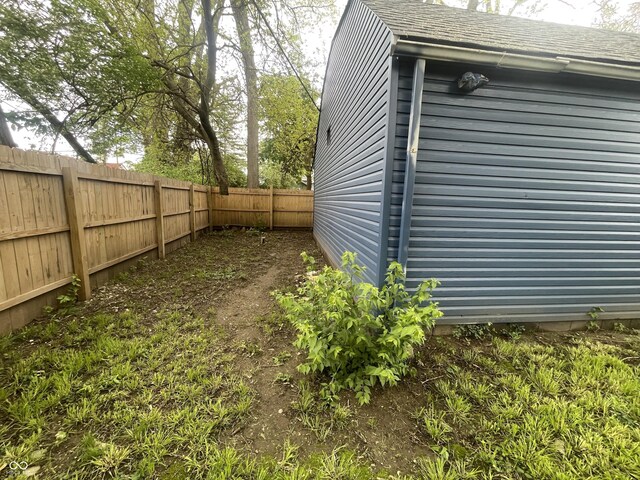 view of side of home featuring a fenced backyard and roof with shingles