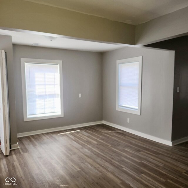 empty room featuring dark wood-style floors and baseboards