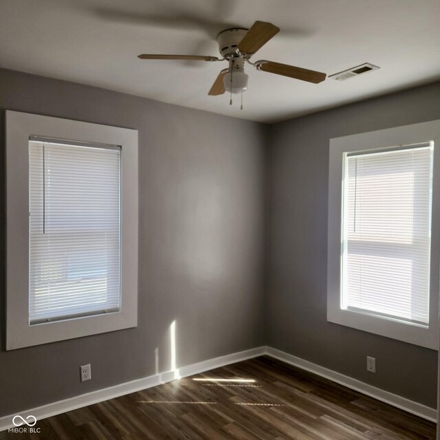 spare room featuring baseboards, ceiling fan, and dark wood-style flooring