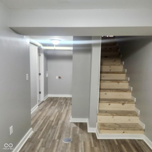finished below grade area featuring wood finished floors, stairs, and baseboards