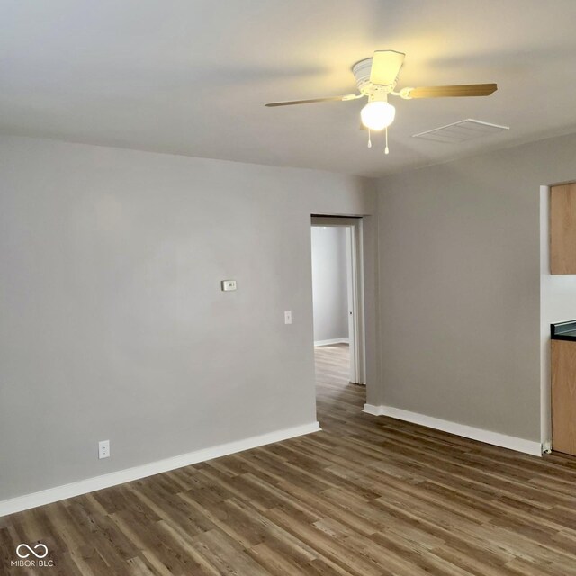 spare room with a ceiling fan, wood finished floors, and baseboards