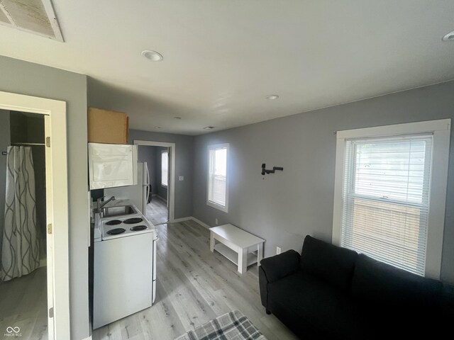 kitchen with electric stove, light wood finished floors, recessed lighting, brown cabinetry, and baseboards