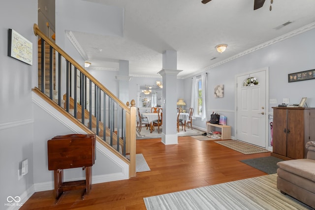 foyer entrance featuring ornamental molding, hardwood / wood-style floors, stairs, ceiling fan, and baseboards