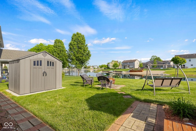 view of green lawn with a shed, a residential view, an outdoor structure, and a water view