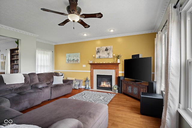 living room with a ceiling fan, wood finished floors, a fireplace, crown molding, and recessed lighting