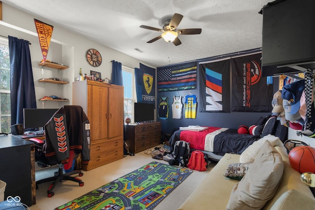 carpeted bedroom with a textured ceiling, ceiling fan, and a desk