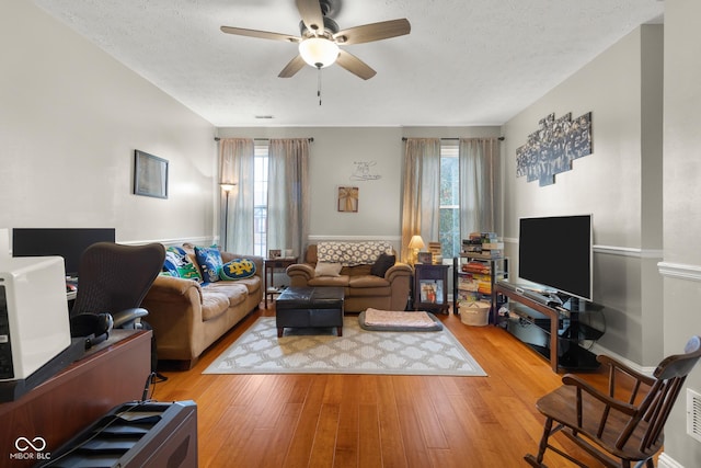 living room featuring a ceiling fan, wood finished floors, and a textured ceiling