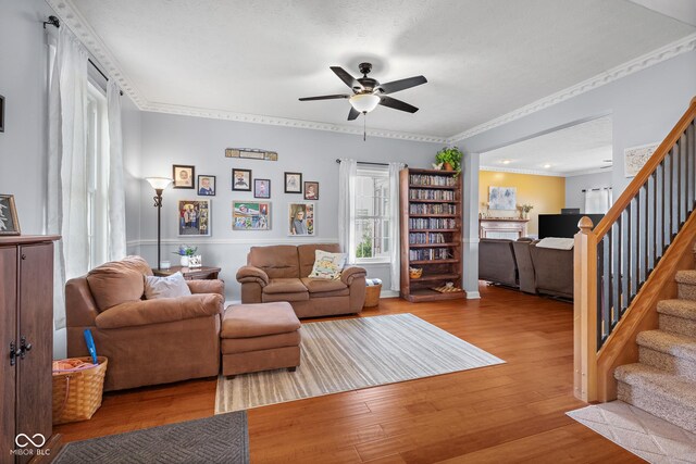 living room with ceiling fan, stairs, wood finished floors, and ornamental molding