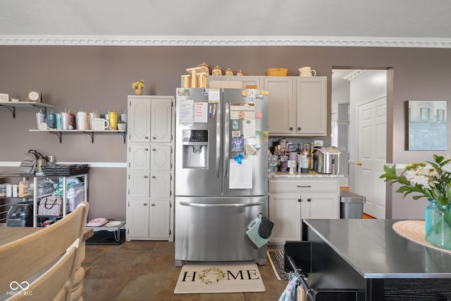 kitchen with stainless steel fridge, white cabinetry, light countertops, and open shelves